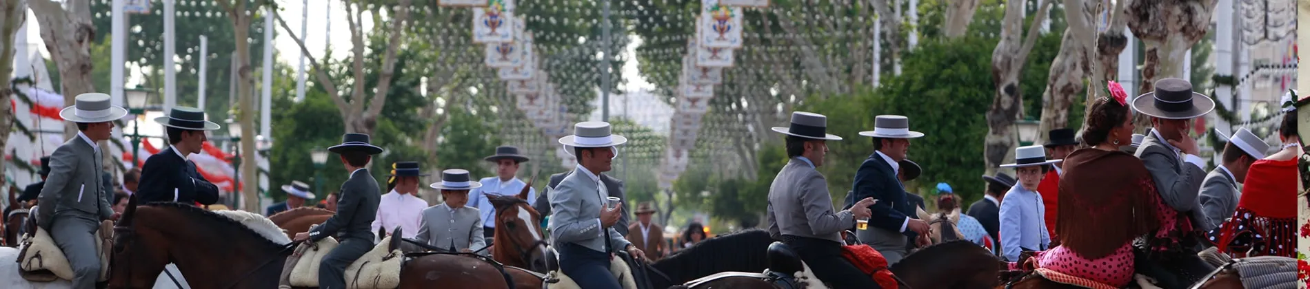Feria de Abril de Sevilla, jinetes a caballo entre farolillos